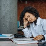 exhausted-lady-book-laptop-cafe-pexels-mikhail-nilov-8297240